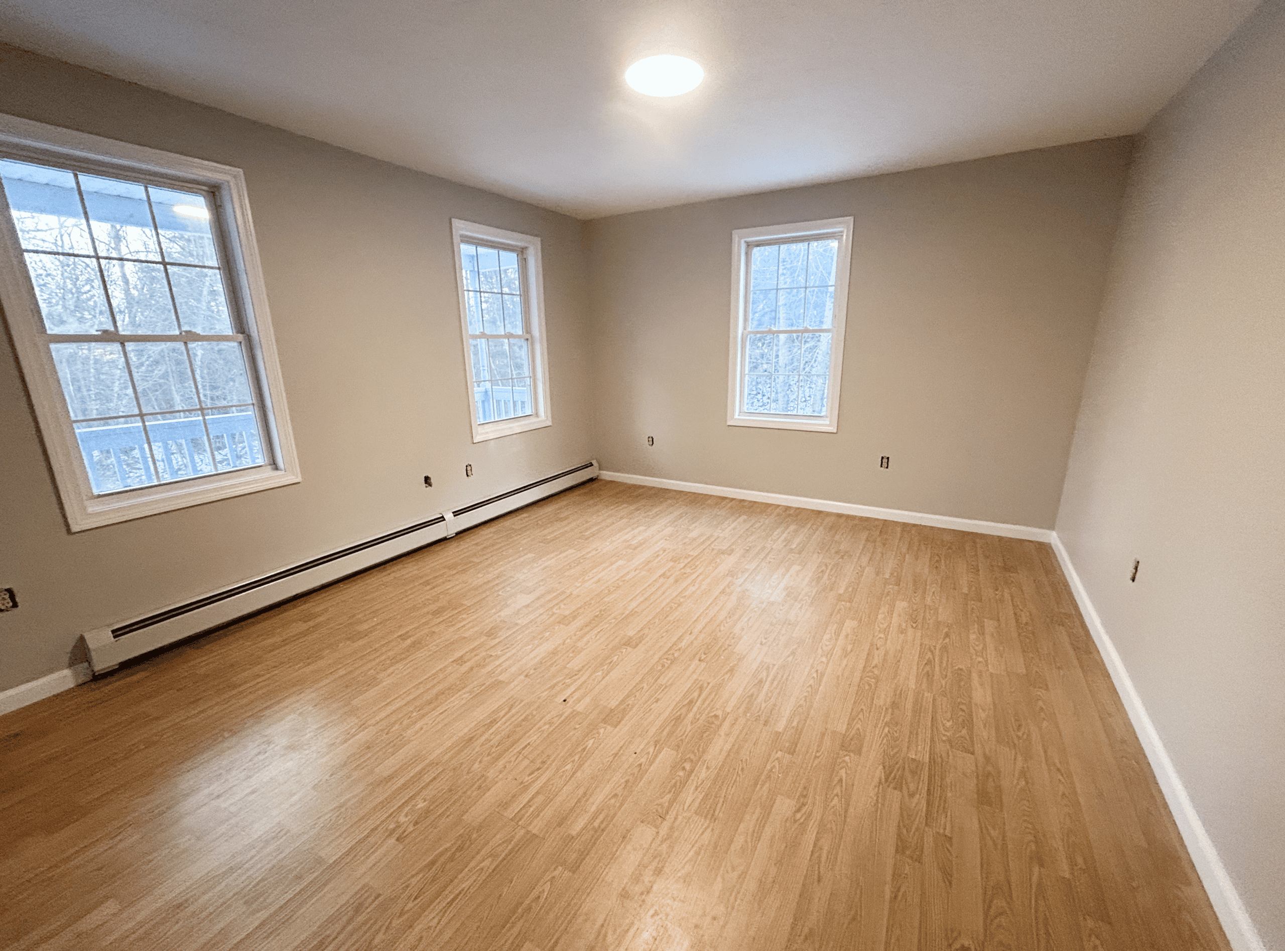 Modern Empty Room Bright empty room with large windows and hardwood flooring.