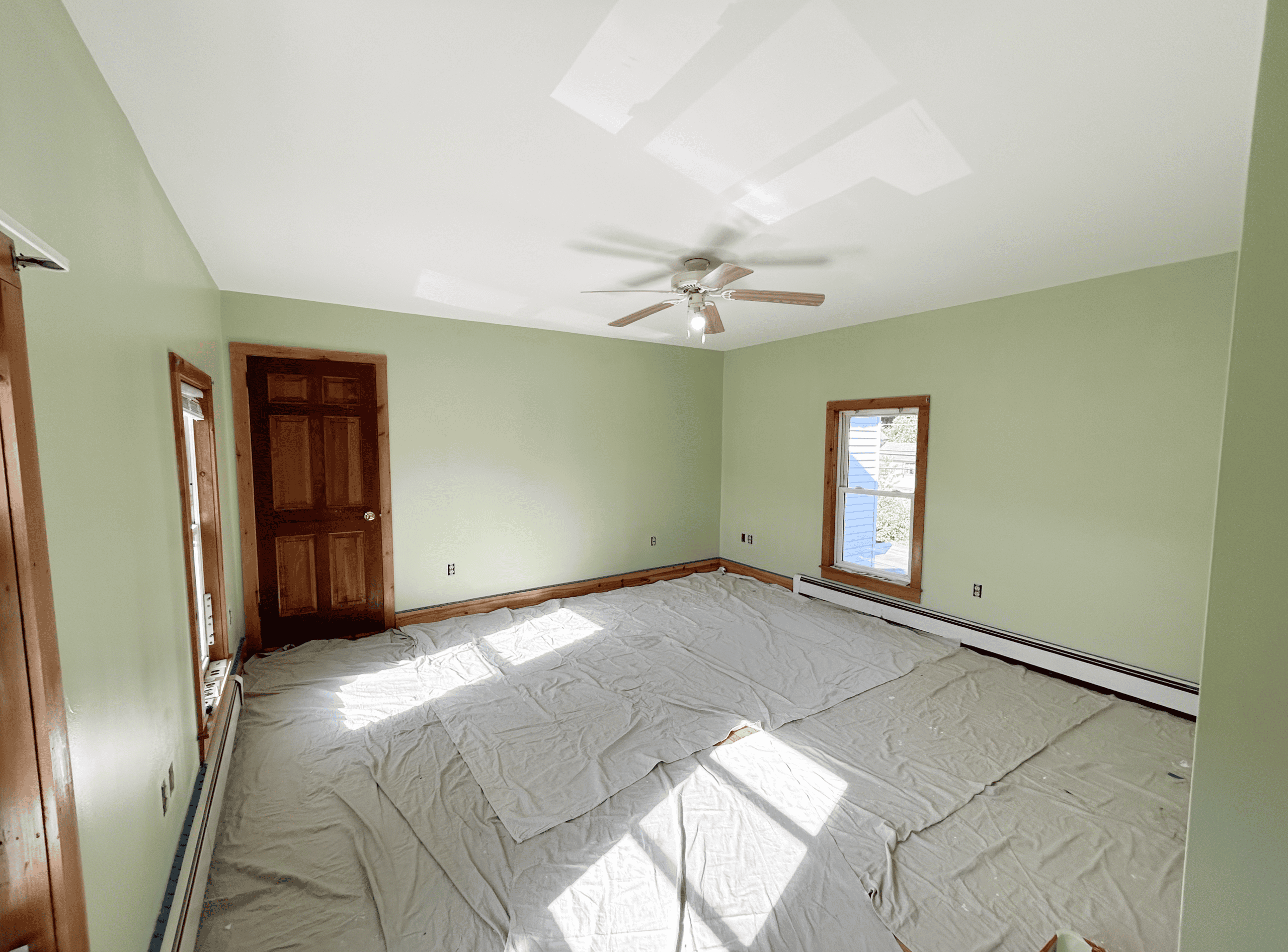 Cozy Green Bedroom Bright green painted bedroom with natural light and wooden accents.